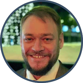 Porträt von Benedikt Kraus, ehrenamtlicher 360° Digital Vision Expert bei l.i.d., im grauen Anzug mit lila Krawatte vor unscharfem Hintergrund.