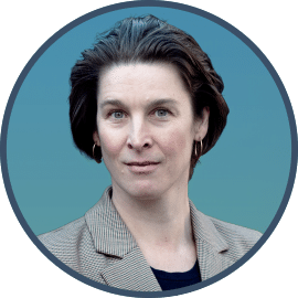 Porträt von Miriam Gronau mit kurzen dunklen Haaren, goldenen Creolen und kariertem Blazer, Kommunikationstrainerin bei Out of the Box Training.